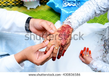 malay wedding groom bolstering gold ring on bride's finger