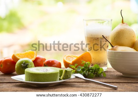 Background fruit have tomato and orange and fruit in bowl and juice with green tea cake.On wooden background outdoor view and holiday with relax