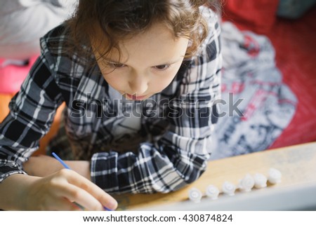 eight year old girl in a plaid shirt with enthusiasm that paints with a brush