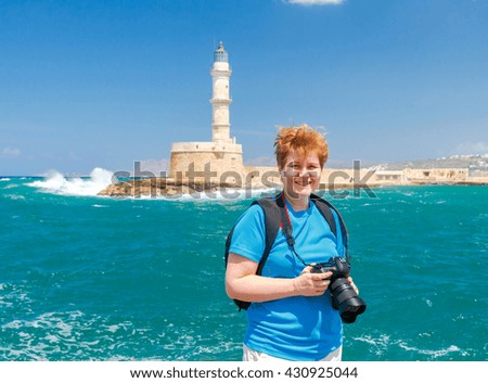 Woman on the waterfront of Chania photographs the old Venetian harbor.