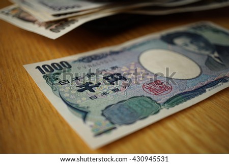 Japanese currency (yen) with its Asian symbols in the form bank notes on the wooden background 