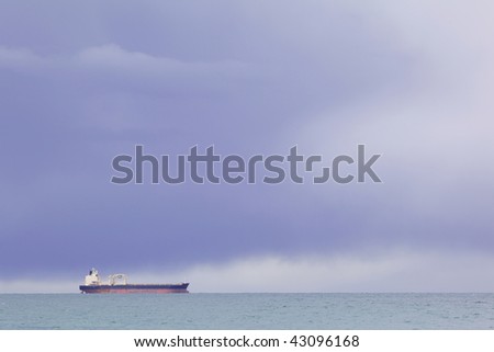 Picture of the ocean and ship on the background of stormy skies.