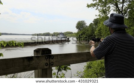 Older man taking photo of a barge on the Missouri River
