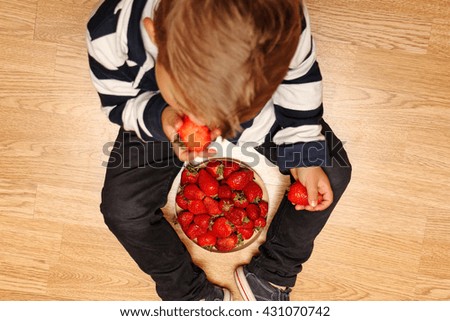 red juicy ripe strawberries useful eats little boy in classic clothes