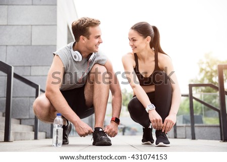 Couple squatting and tying their shoelaces Royalty-Free Stock Photo #431074153