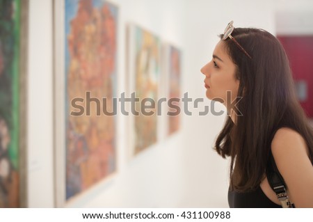 Young woman looking at modern painting in art gallery Royalty-Free Stock Photo #431100988