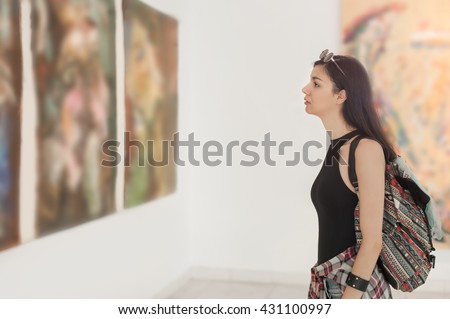 Young woman looking at modern painting in art gallery Royalty-Free Stock Photo #431100997