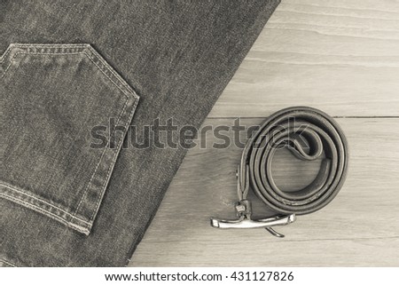 Jeans with a leather belt on a wooden background./ Convert image files into black and white.