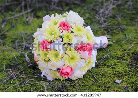 Wedding bouquet of rose, chrysanthemum , iris, and gypsophila on the forest moss