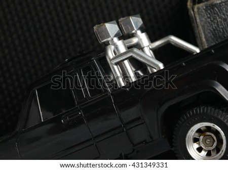 The old and dirty black color radio control model toy pick up car among the dark background scene.