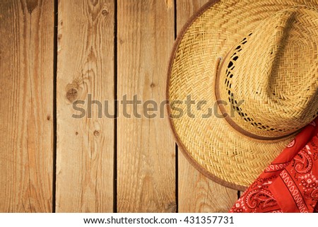Cowboy hat on wooden vintage table with red bandanna for party invitation. View from above