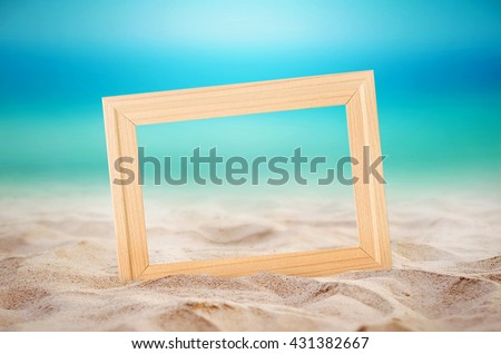 Empty wooden picture frame on the beach sand, summer concept.