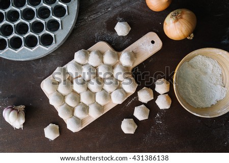 Top view ready tasty raviolis or dumplings filled with minced meat on flour on wooden board