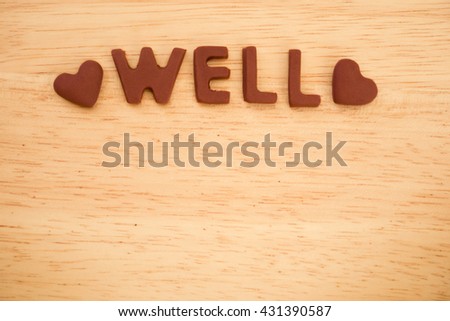 well wording made of fondant sugar with heart on wooden board - top view