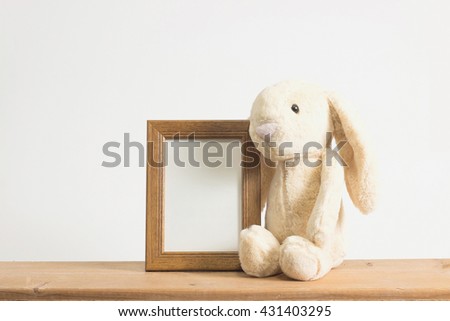 Single brown rabbit with photo frame on wooden table. 