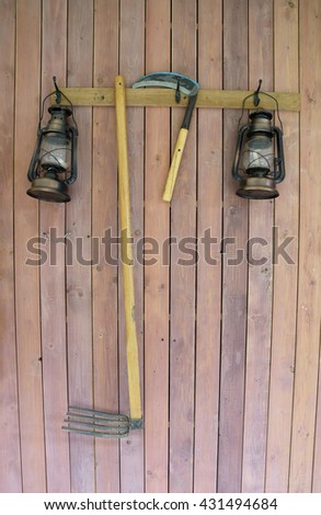 The traditional farm implements and oil lamp on wood wall 