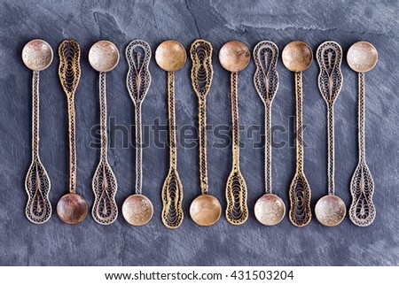 Set of eleven old tarnished and patinated Ottoman teaspoons with an engraved pattern on the handle and round bowl arranged in a line on a slate background