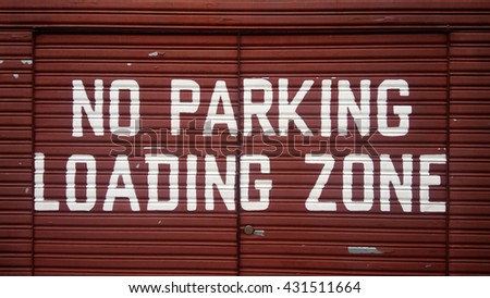 No parking loading zone sign on red metal door