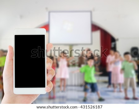 woman use mobile phone and blurred image of children are dancing in the church
