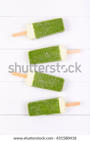 Frosty popsicles of kiwi in a row on a white wooden background