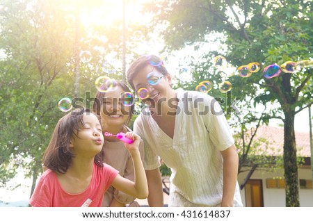 Portrait of joyful happy Asian family playing bubbles together at outdoor park during summer sunset. Royalty-Free Stock Photo #431614837