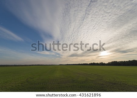 Vast mowed grass land with evening sky and clouds
