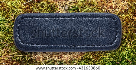 Blue blank leather label on moss background