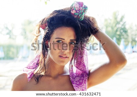 portrait of pretty woman wearing colored foulard in the hair near the pool