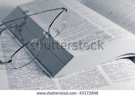 closeup monochrome photo of opened books with glasses
