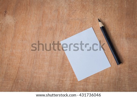 Blank note and pencil on wood background close up still life