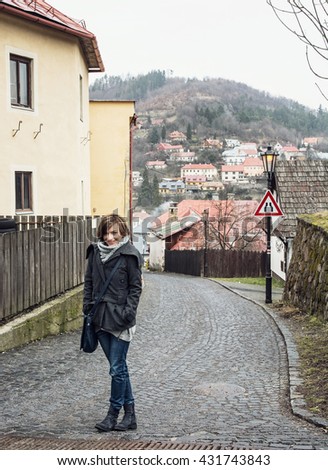 Young tourist woman posing in historical street in Banska Stiavnica, Slovak republic. Travelling theme. Travel destination. Positive woman. Traffic sign.