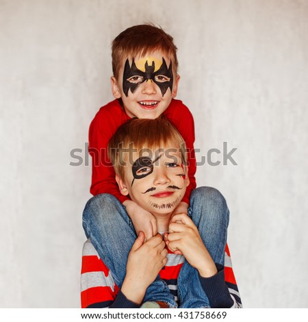 Two boys with face art of a hero and pirate. Having  their faces painted on birthday party.