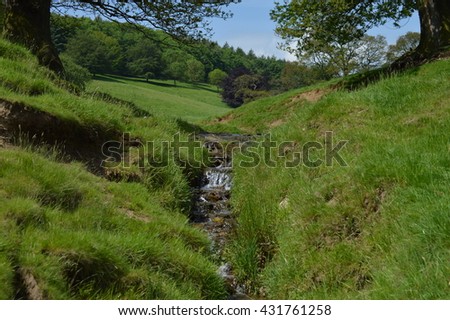 A beautiful lancashire landscape featuring a stream and waterfall surrounded by hills and trees in an iconic english countryside on a british spring summer day