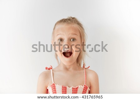 Little European girl opening mouth in surprise and raising her eyebrows with wonder. Blond child with naive glance, trustful simplicity and amazed face. Royalty-Free Stock Photo #431765965
