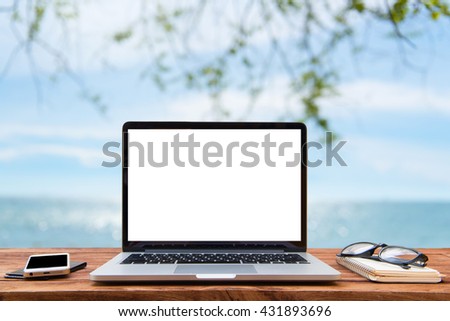 Laptop with blank screen on table by the sea is beautiful.