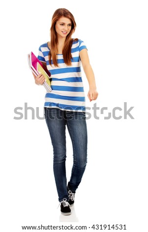 Teenage happy woman holding textbooks and pointing for something
