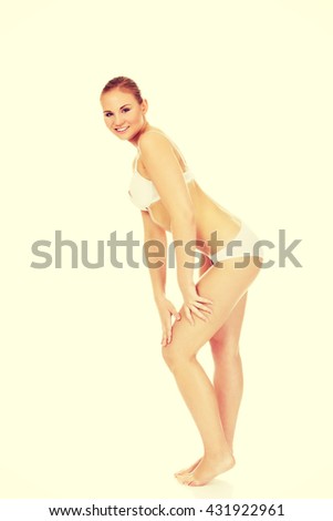 Young athletic woman in white underwear touching her thigh