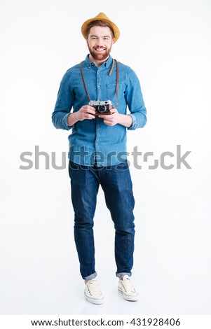 Handsome young hipster guy holding retro camera wearing hat isolated on the white background