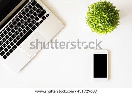 Top view of white desktop with laptop keyboard, blank cell phone and plant. Mock up