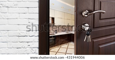 Half opened door to a kitchen. Door handle, door lock. Dining room door half open. Opening door. Welcome concept. Entrance to the room. Door at white brick wall, modern interior design.