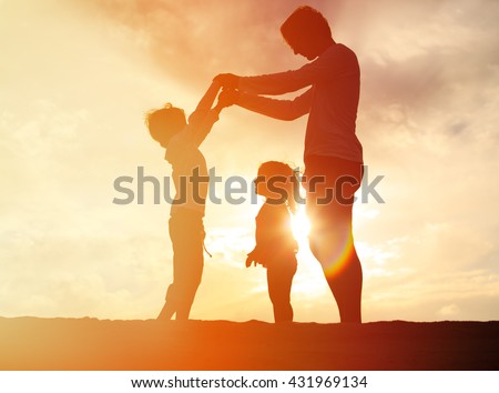 father and two kids playing on sunset sky