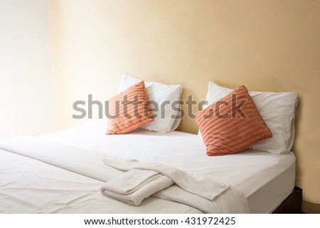 white pillow and orange pillow on bed and with blanket in vintage bedroom with lighting in morning
