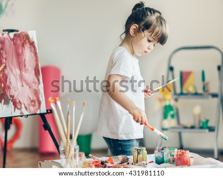 Cut girl painting in at her  home. Selective focus and small depth of field. Royalty-Free Stock Photo #431981110