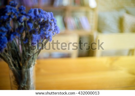 purple flower in the glass cup in front of blur bookshop background