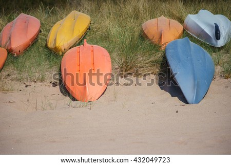 Upside down colorful kayak or canoe boats lays on sandy beach, selective focus