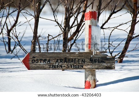 Snow-covered signpost at snowmobile track in northern Sweden