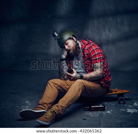 Tattooed bearded hipster skateboarder drinking beer.