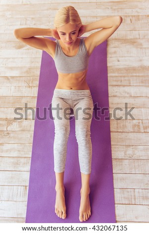 High angle view of beautiful young woman in sports wear doing sit ups while working out on yoga mat