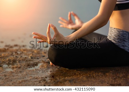 Close up  of a woman's body and hands meditating and doing yoga at the beach