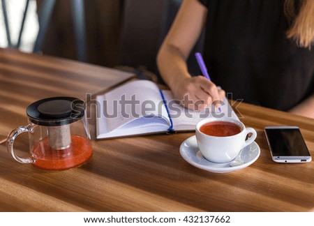 beautiful young woman woman drinking tea and working with business papers . breakfast in restaurant